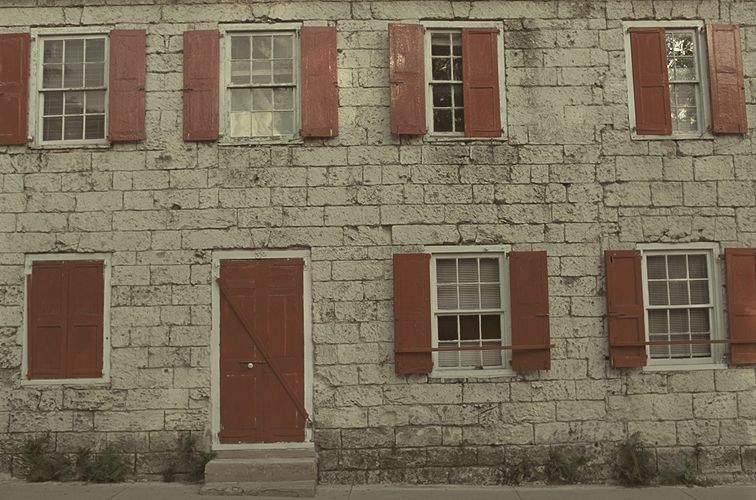 Stone house front with red shutters
